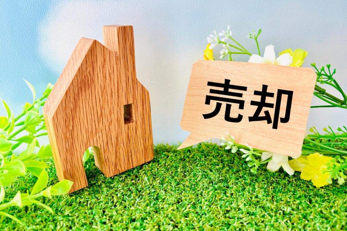 戸塚区の不動産売却をイメージした木製の家の模型と「売却」のプレート
