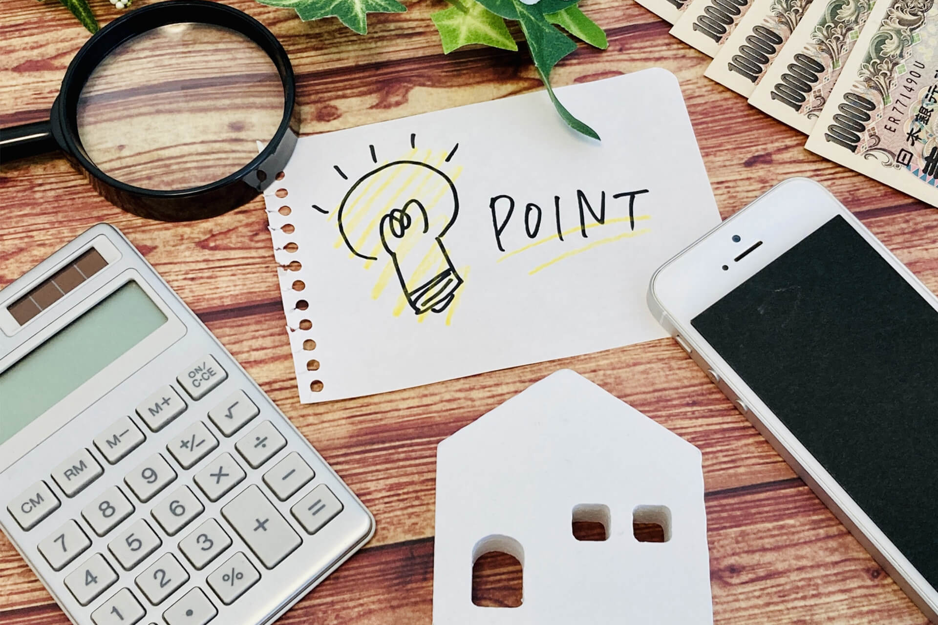 「POINT」と書かれたメモと家の模型、電卓、スマートフォン｜戸建てを高く売却するコツを表すイメージ