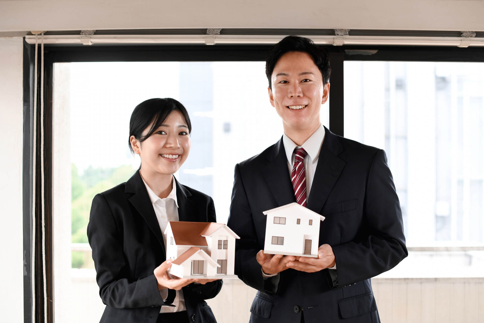 住宅模型を持つ不動産担当者｜ミツバハウジングの不動産売却・買取サポートのイメージ