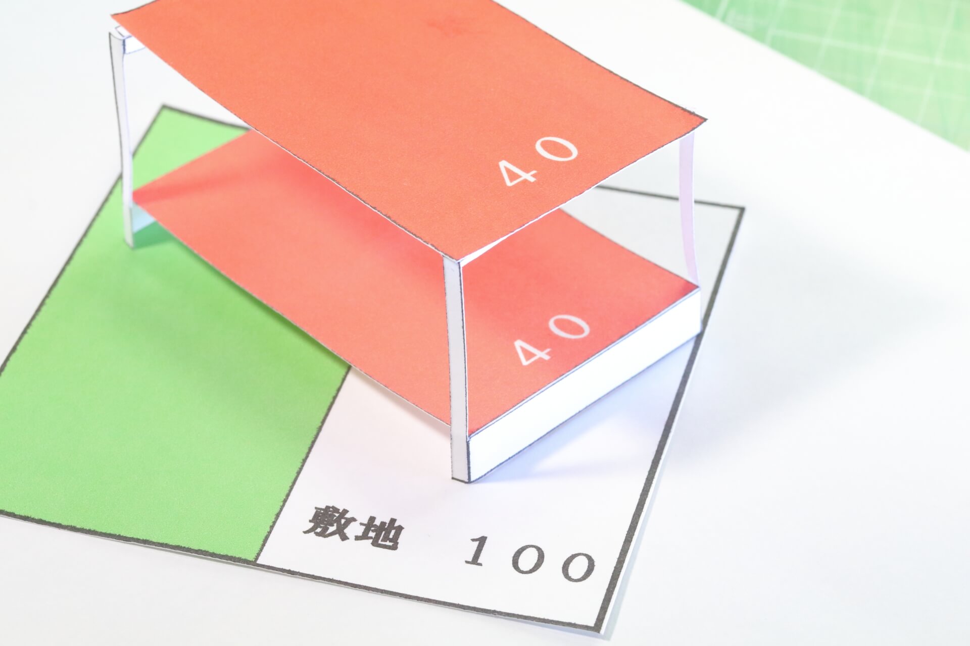 敷地100に対して建築面積40を示した建物模型｜土地の用途地域や建築規制を確認するイメージ