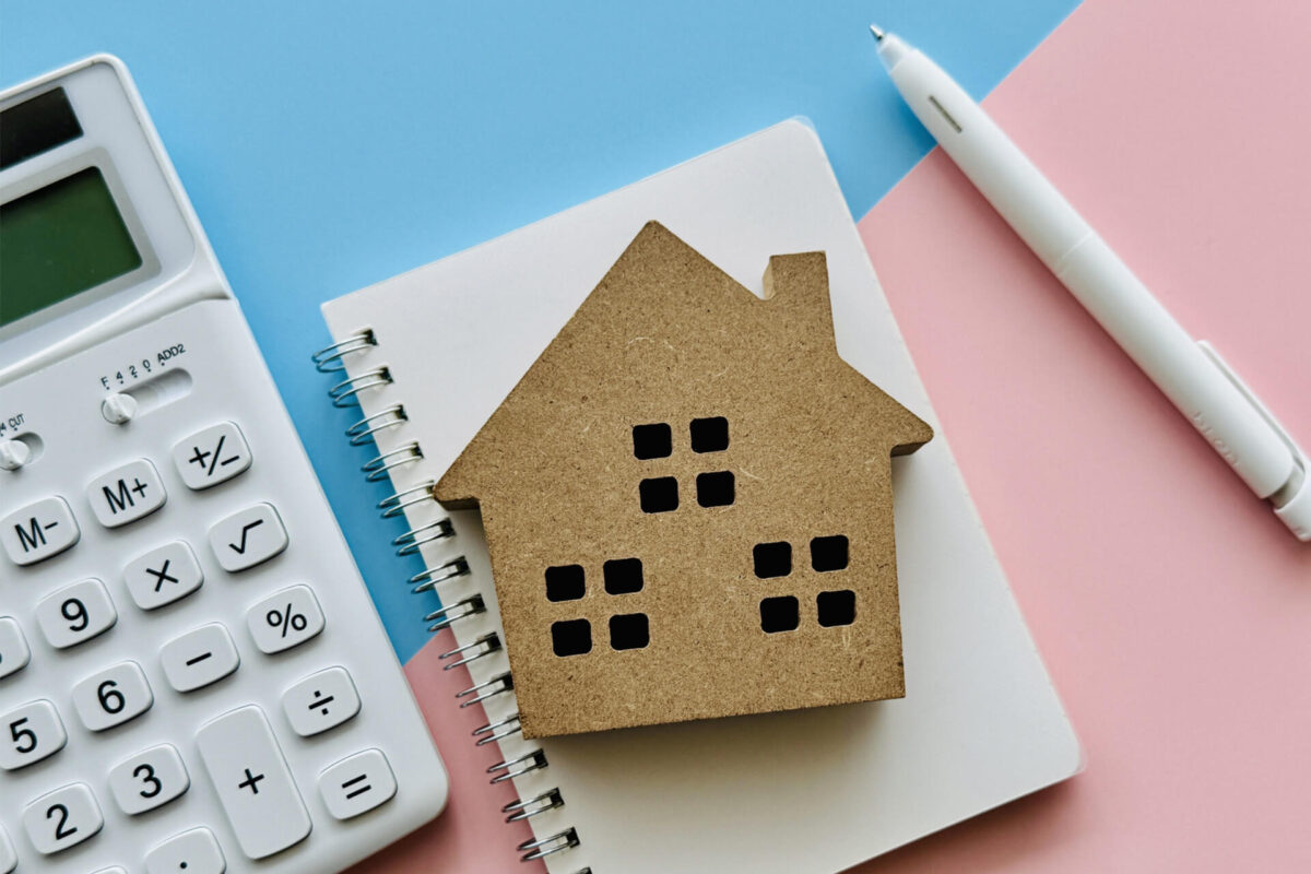 住宅模型と電卓・ノート｜不動産買取と仲介のどちらが適しているか検討するイメージ